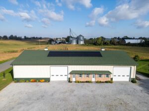 Aerial view of a farm building with rooftop solar, grain silos and fields