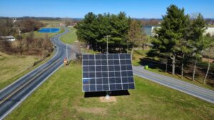 24-panel pole-mounted dual-axis solar tracker in a yard beside a road