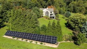 Aerial view of a residential ground-mount solar array and home among trees